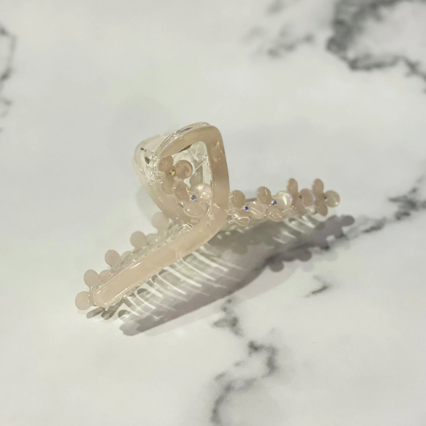 Beige pearl floral hair clutches with dainty flower details on a marble surface