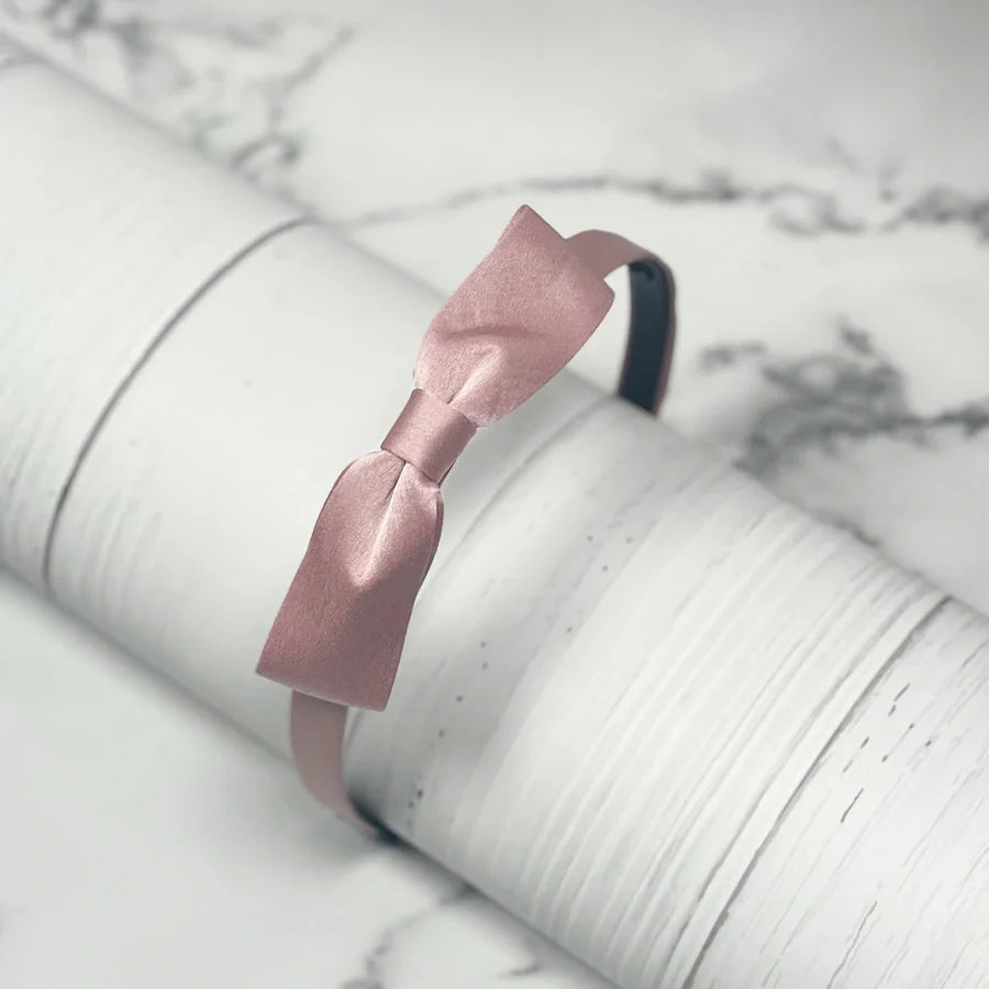 Pink satin bow hairbands on white textured surface from mydevelopmentstor collection