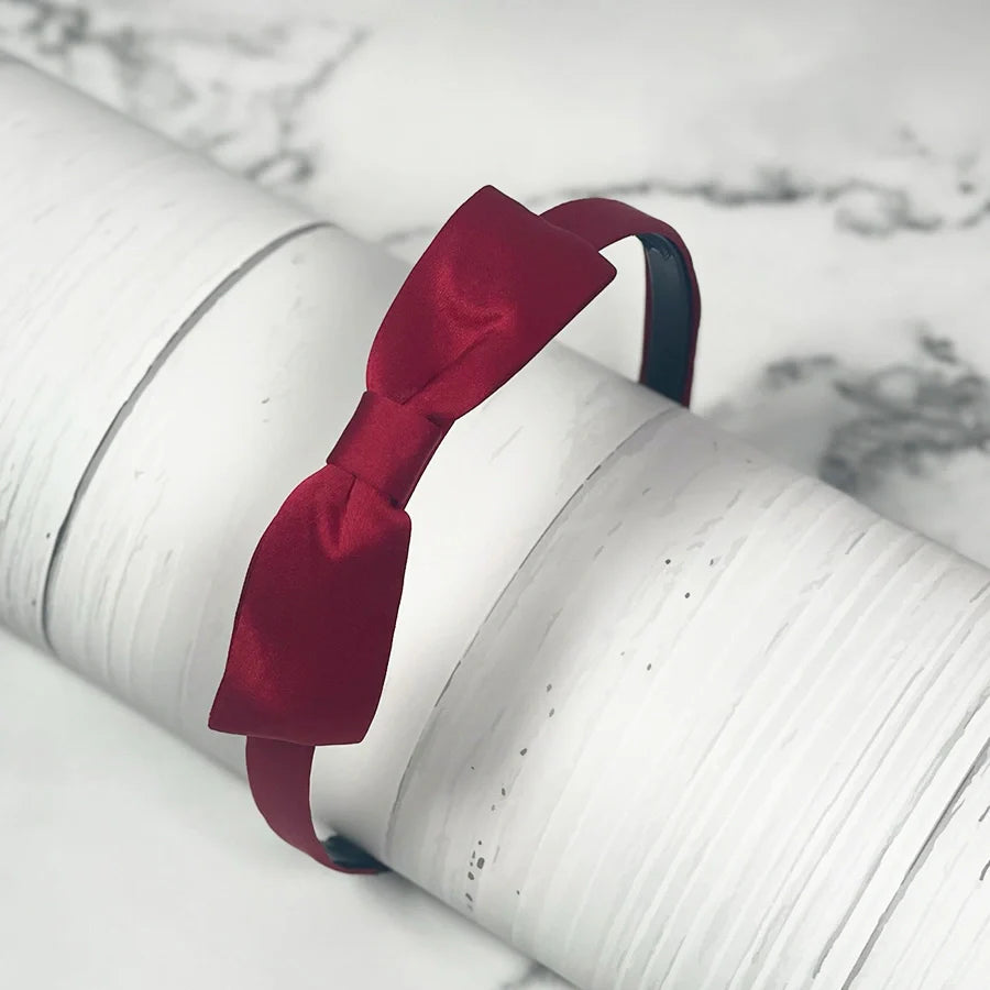 Elegant deep red satin bow hairbands with smooth finish on a slender headband