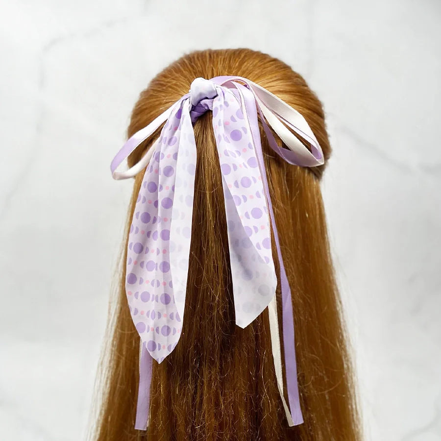 Purple and white polka dot scrunchies with ribbon for women tied on long red hair
