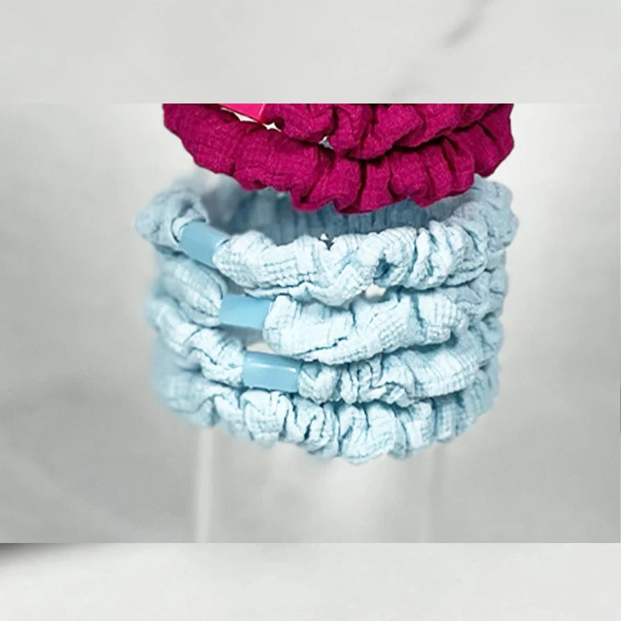 Soft cloth hair ties in blue and pink colors stacked together for gentle hair hold