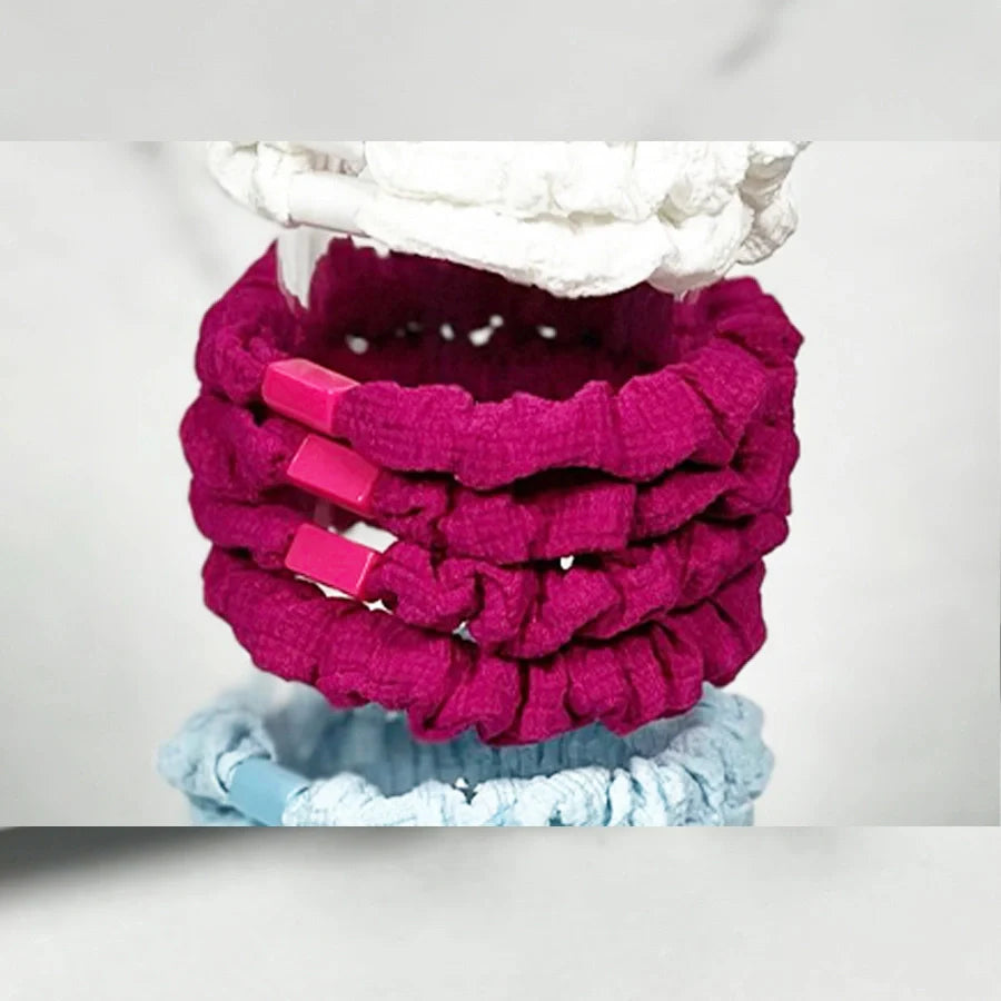 Stack of pink and blue soft cloth hair ties with textured fabric and clips for gentle hair styling