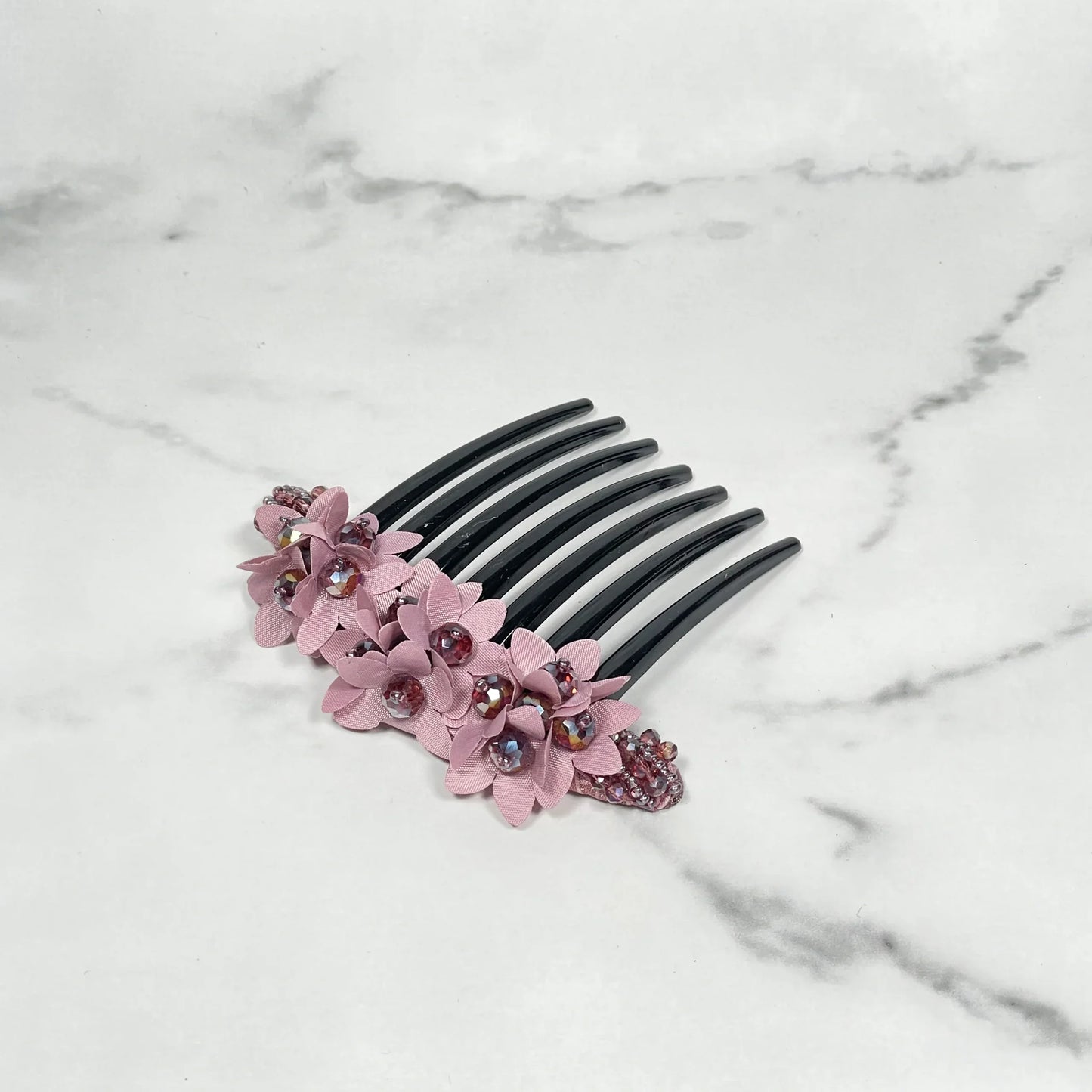 Studded hair bun comb with pink floral decorations and sparkling rhinestones on black teeth
