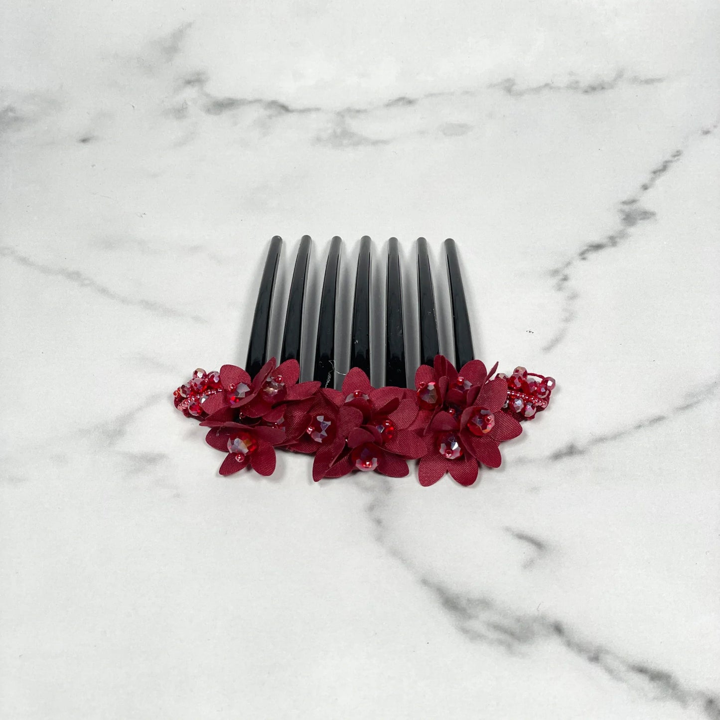 Black studded hair bun comb with red floral decoration and small embedded gems