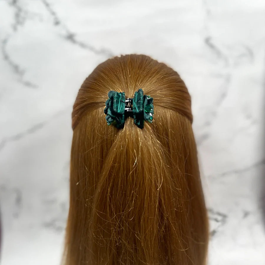 Green studded hair clutches securing half-up hairstyle on long light brown hair