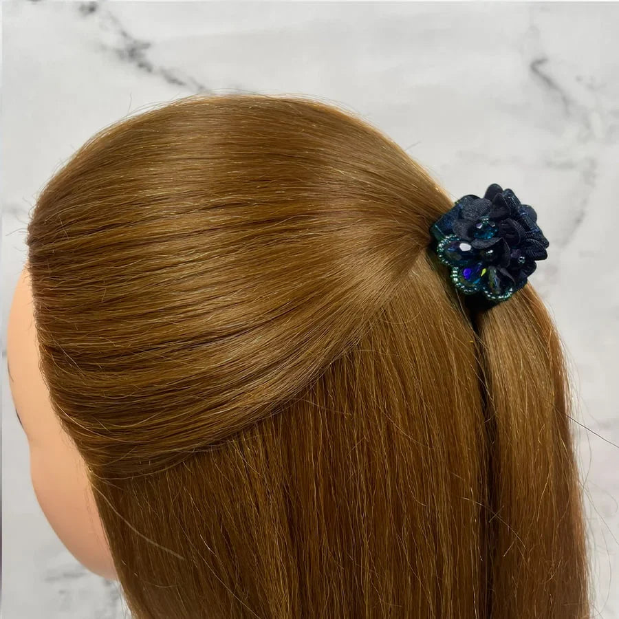 Dark studded hair clutches securing brown hair in a half-up hairstyle against a marble background