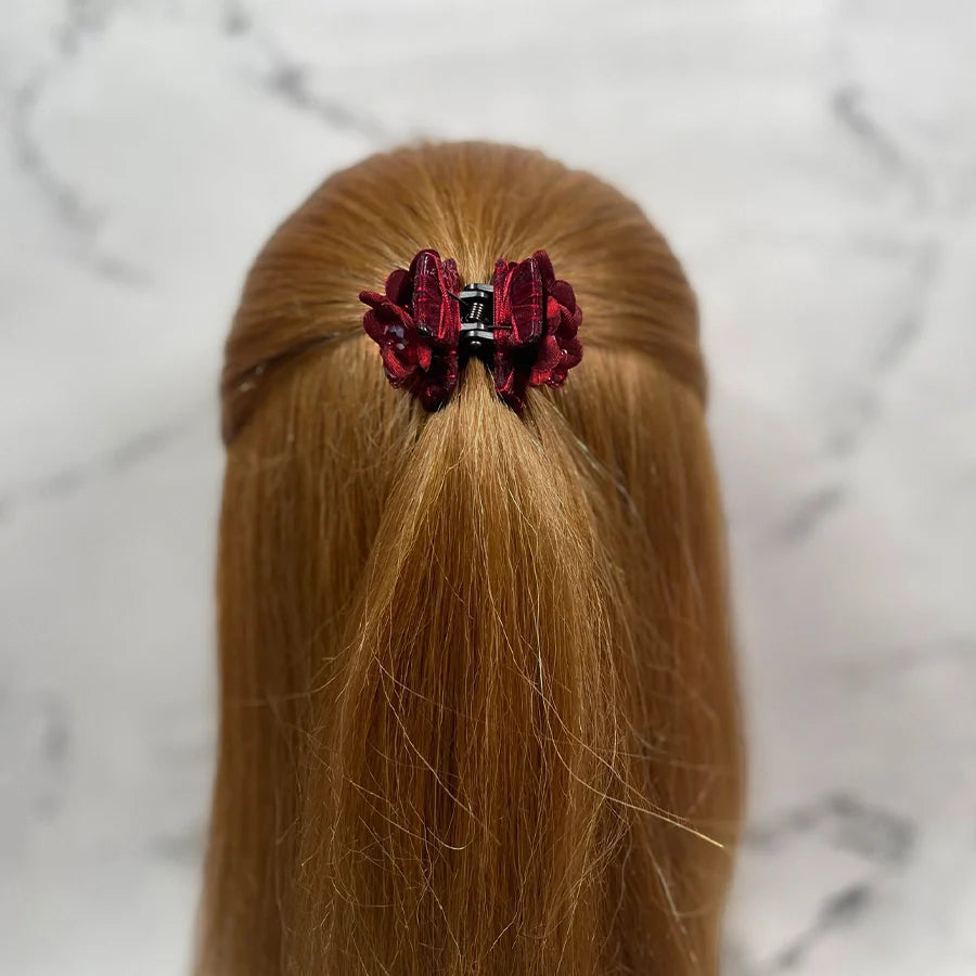 Red floral studded hair clutches holding back half-up long blonde hair on marble background
