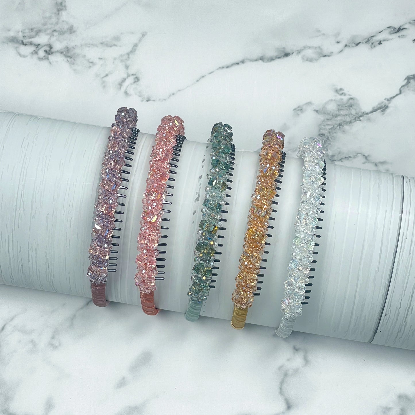 Set of five colorful studded headbands with sparkling beads displayed on a white marble surface
