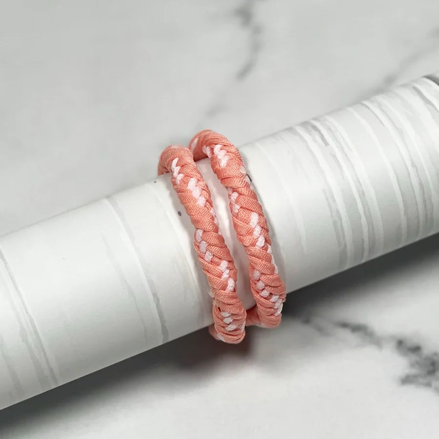 Two pink braided Thick Hair Ties displayed on a white cylindrical stand