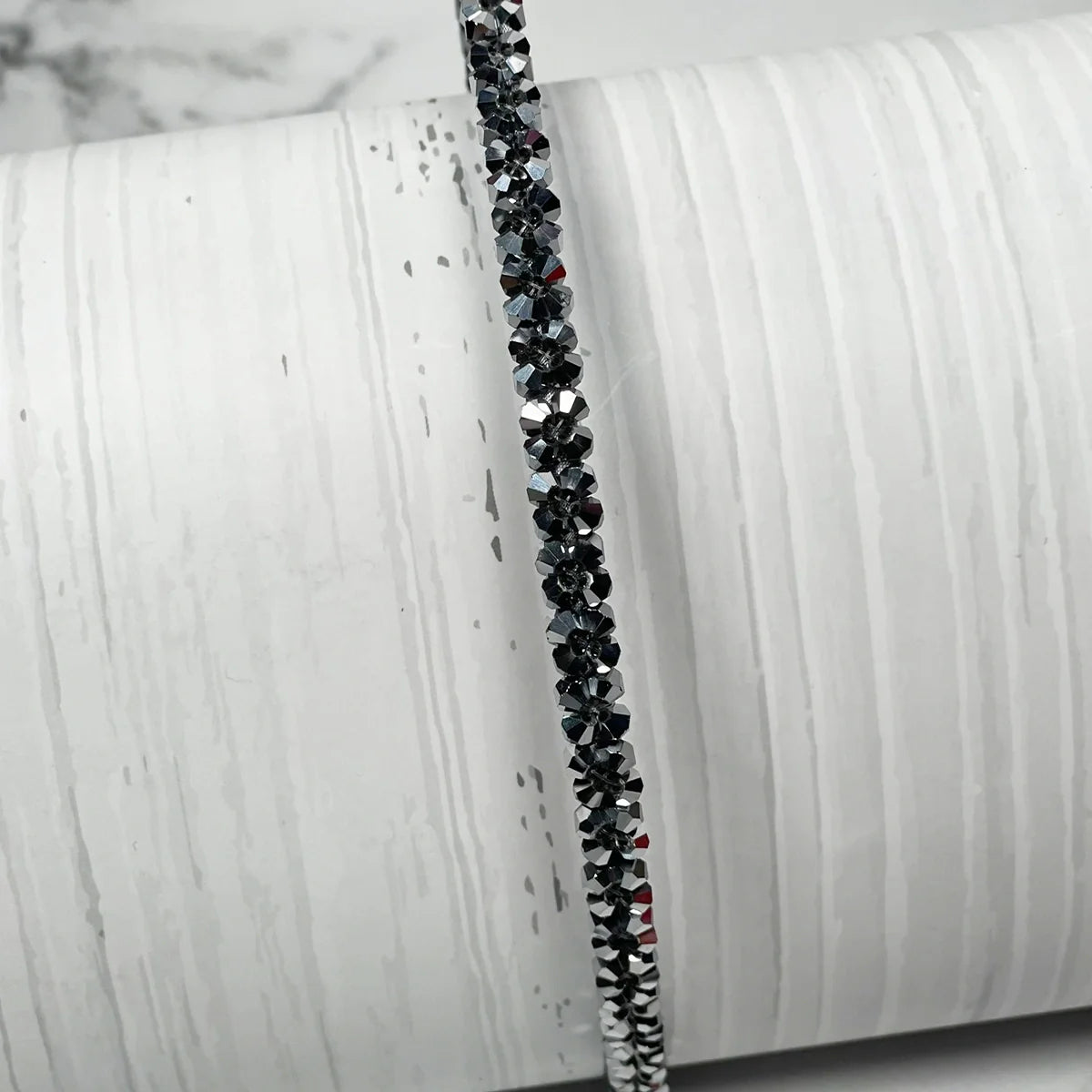 Black thin embellished headbands for women with sparkling crystals displayed on a white textured background