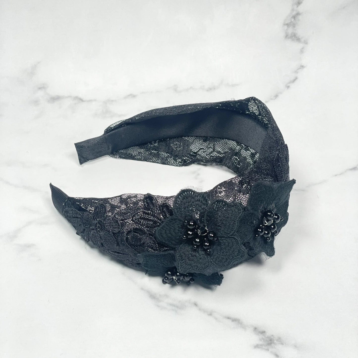 Black lace three flower broad hairbands with bead accents on a white marble background