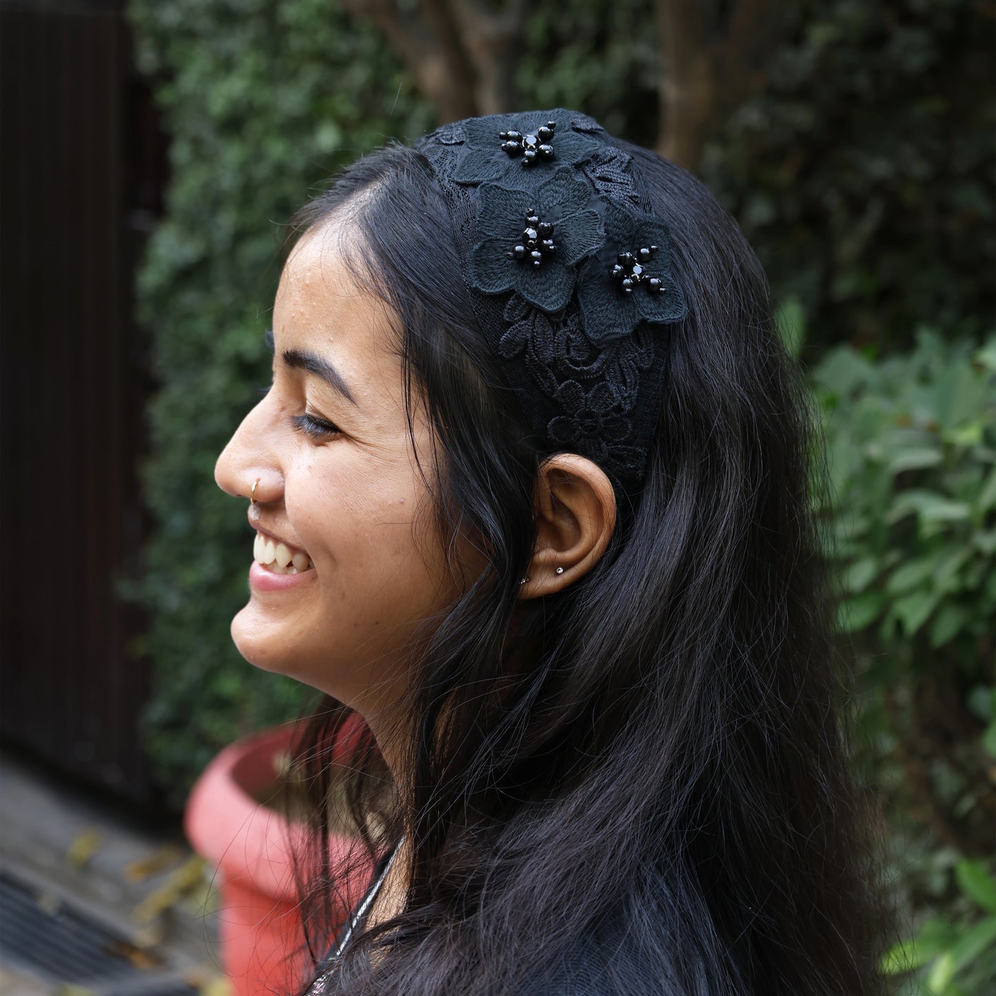 Black three flower broad hairbands with bead details worn by smiling woman with long hair