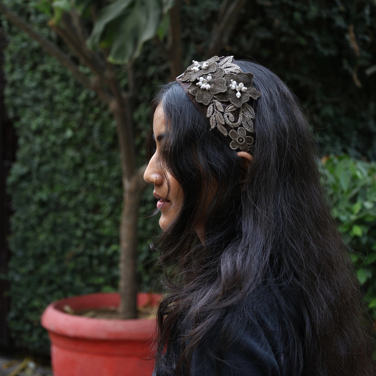 Woman wearing decorative three flower broad hairbands with floral lace design in outdoor setting