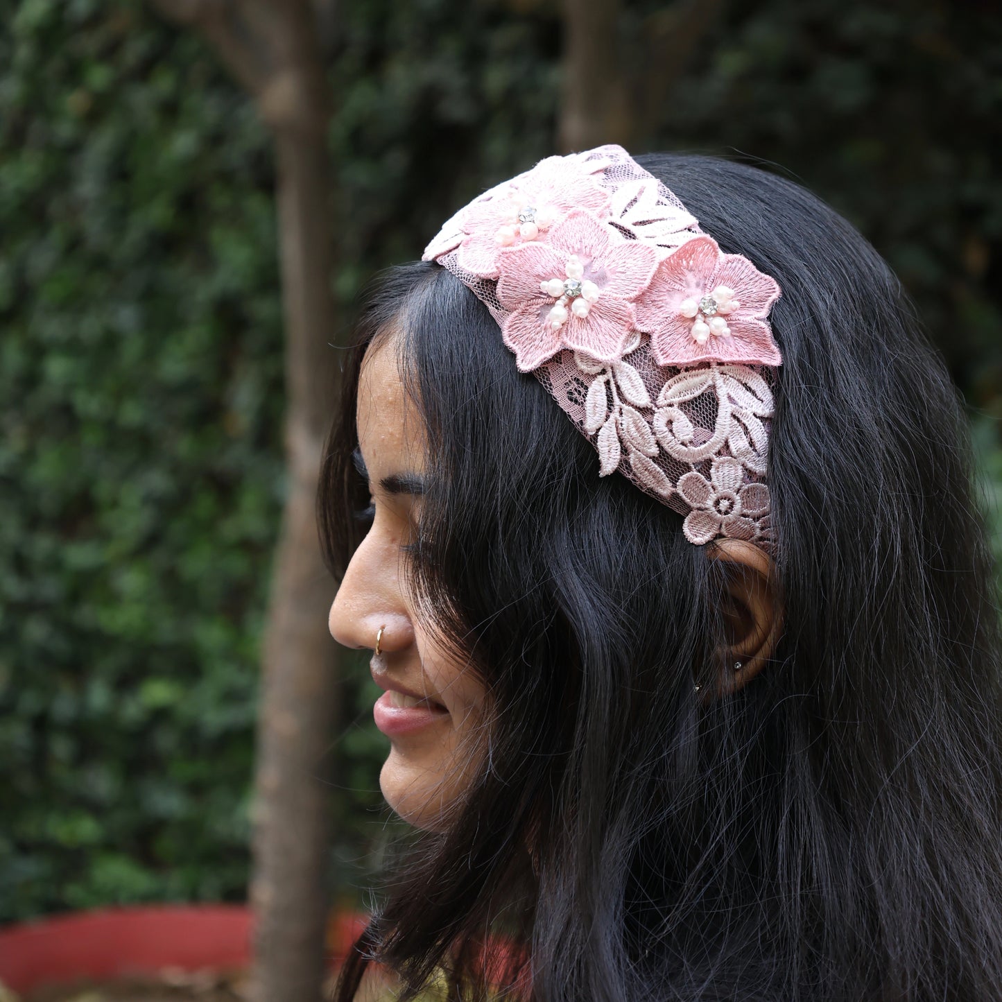 Woman wearing pink lace three flower broad hairbands with decorative floral design outdoors