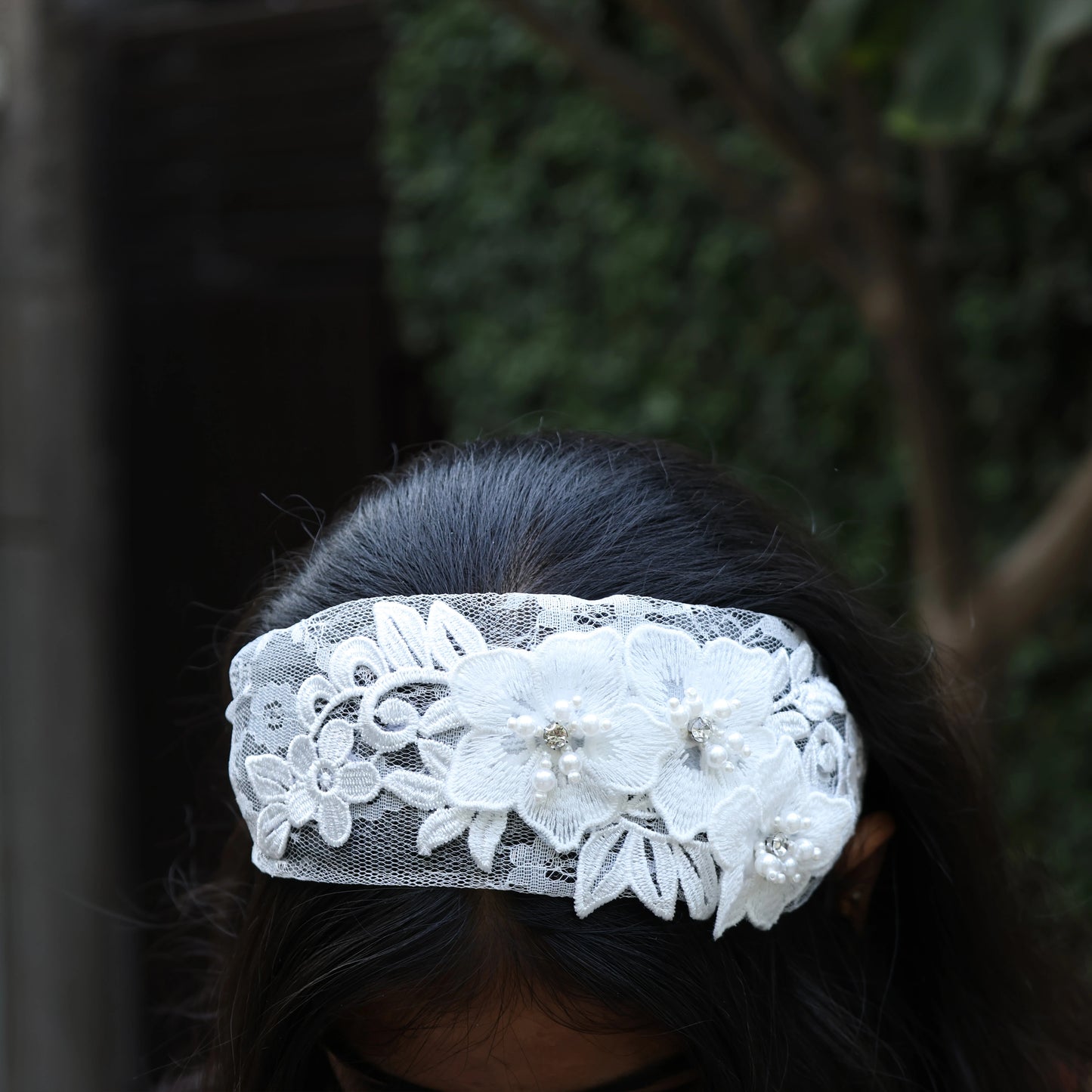 White lace three flower broad hairbands with pearl embellishments worn on dark hair