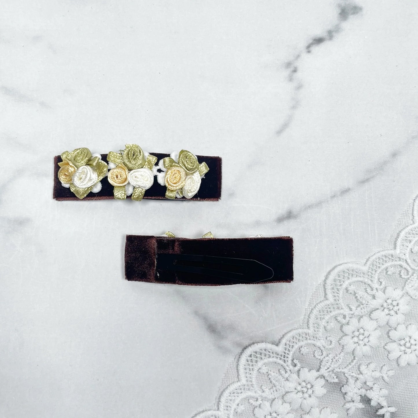 Velvet flower hair pins with small yellow and white rose designs on dark velvet base