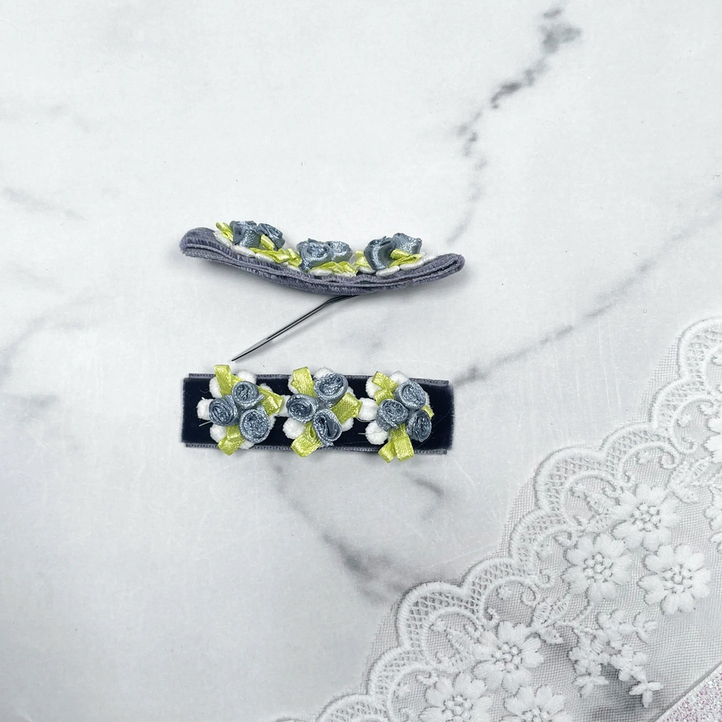 Velvet flower hair pins in blue and green with small fabric roses on a white lace background