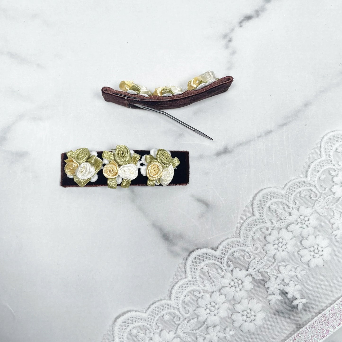 Velvet flower hair pins with green and cream rose designs on black fabric background