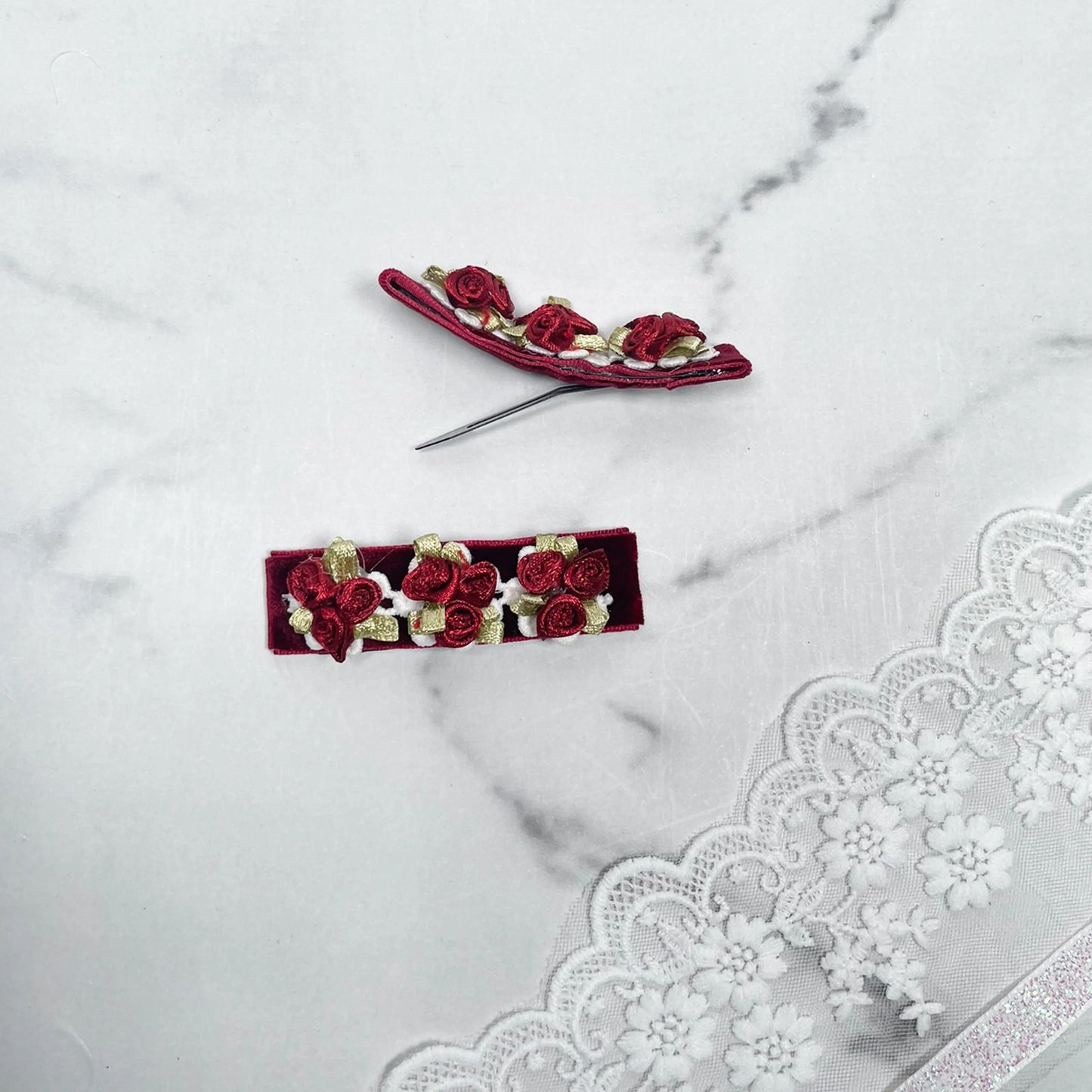 Red velvet flower hair pins with small roses and green leaves on white lace background