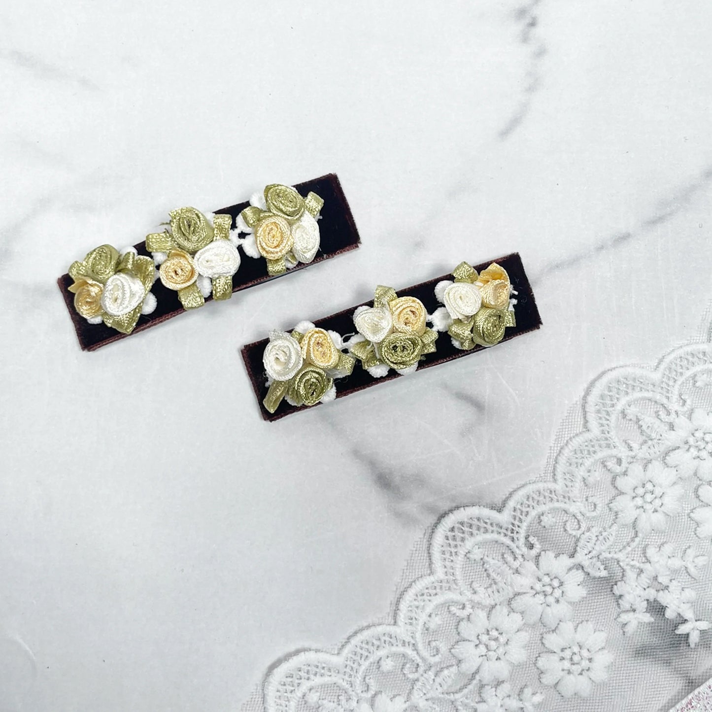 Velvet flower hair pins with cream and green floral design on dark velvet background