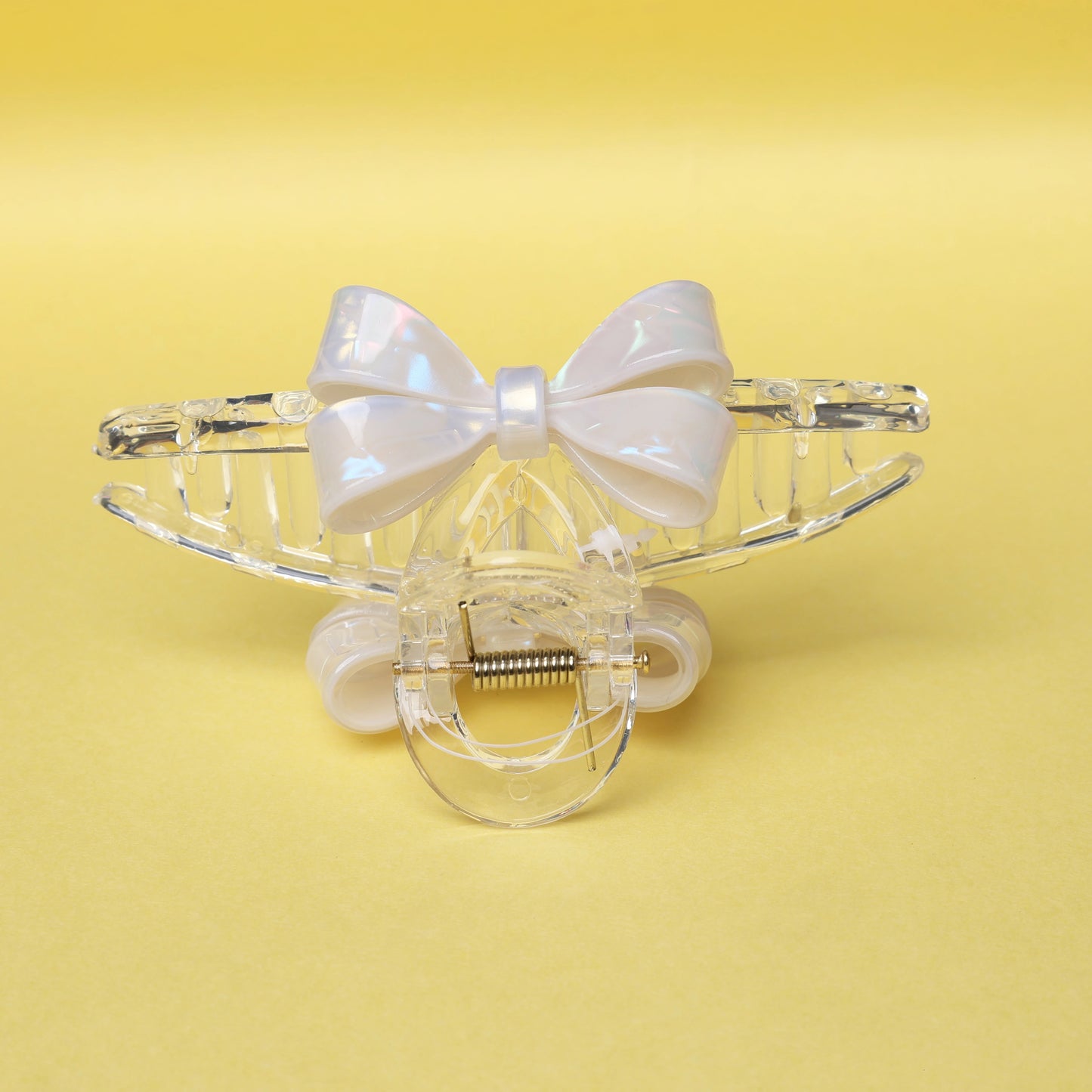 Clear plastic hair claw clip with a white bow hair clutches accessory on yellow background