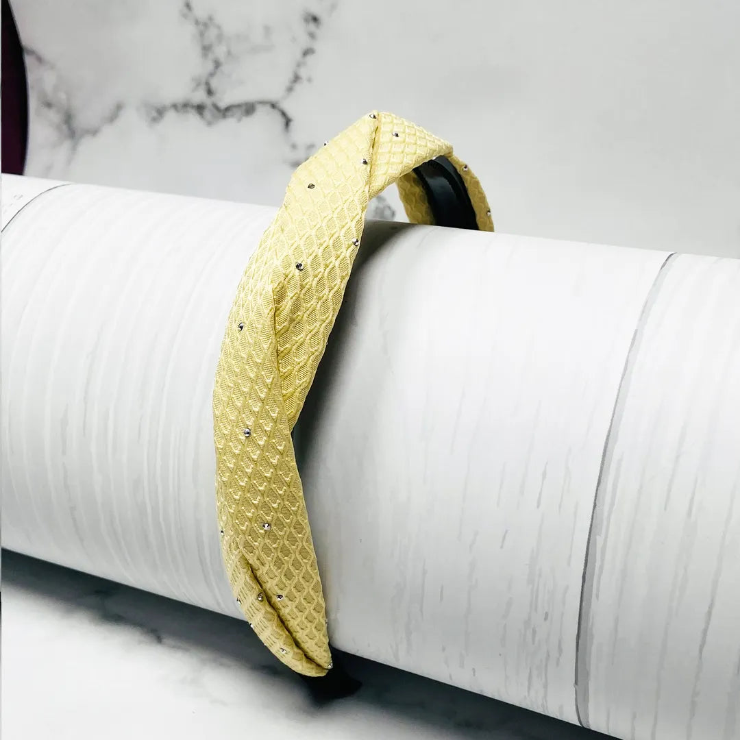 Yellow textured Light Studded Hairbands with small decorative studs displayed on a white cylindrical stand