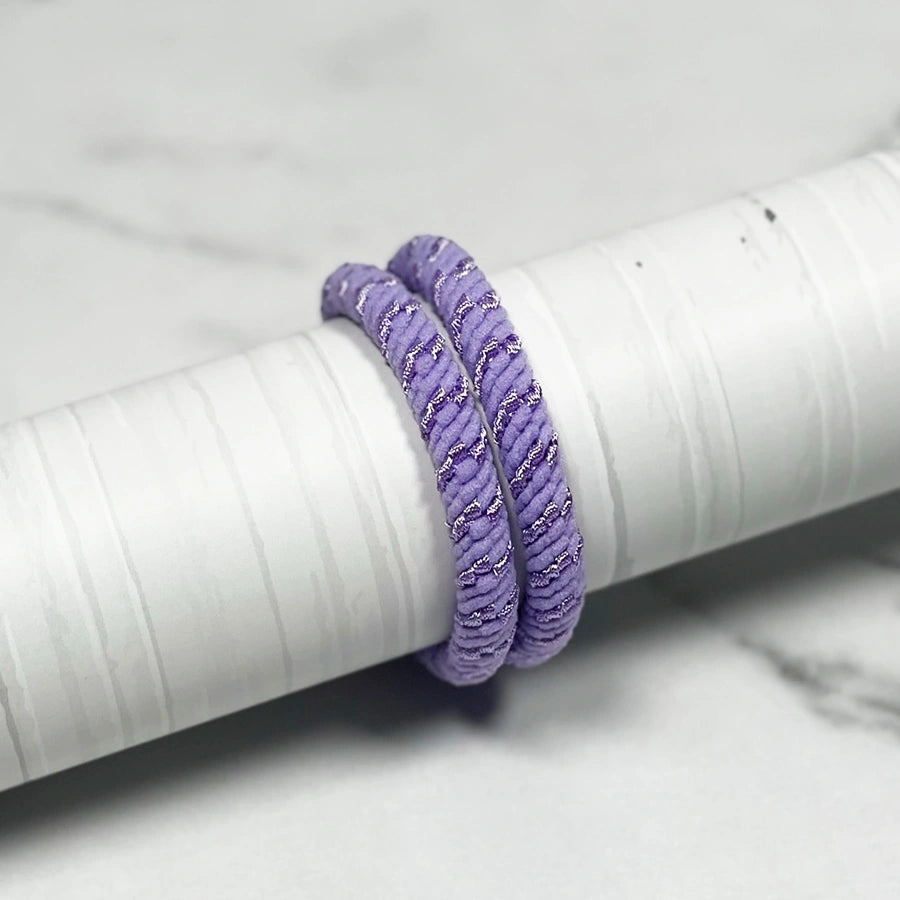 Purple thick pastel hair ties with textured design wrapped around a white cylindrical object