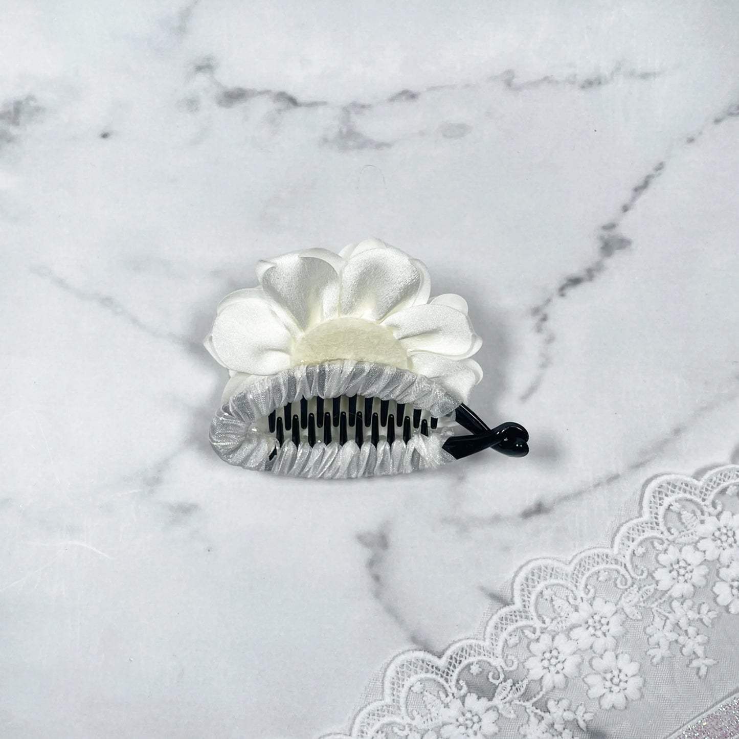 Bella Luxe white crystal banana clip with flower design on marble background