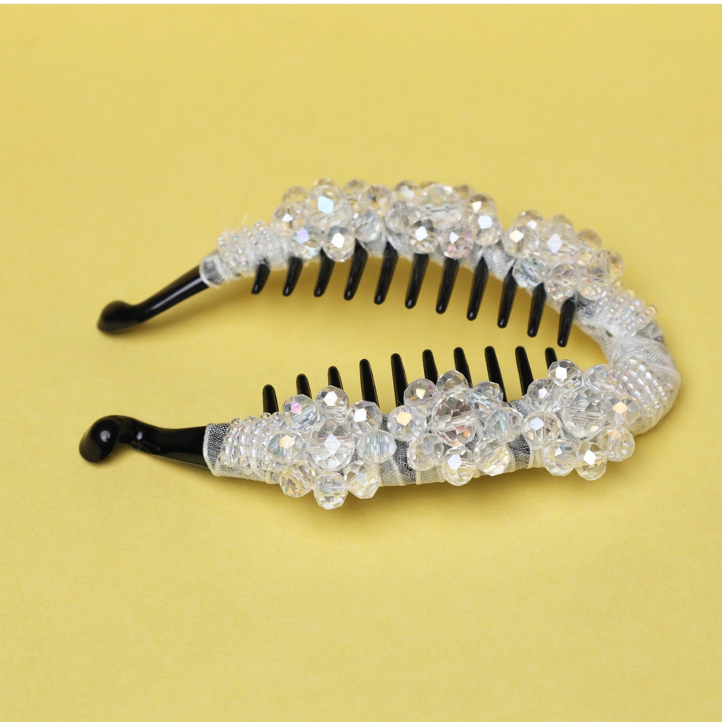 Bella Luxe white crystal studded banana clip with black teeth on a yellow background