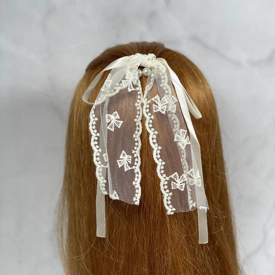 Lacy pearl hair ties with delicate lace bows and pearl accents on brown hair
