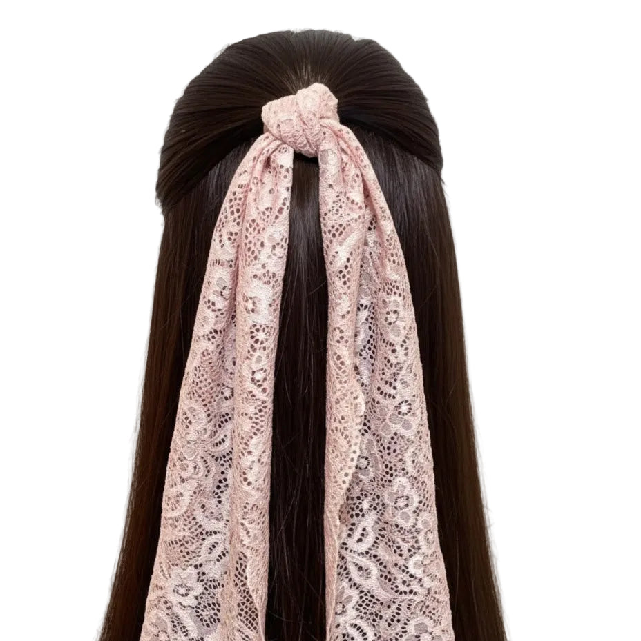 Pink lace headband worn by a person with long dark hair against a white textured wall.