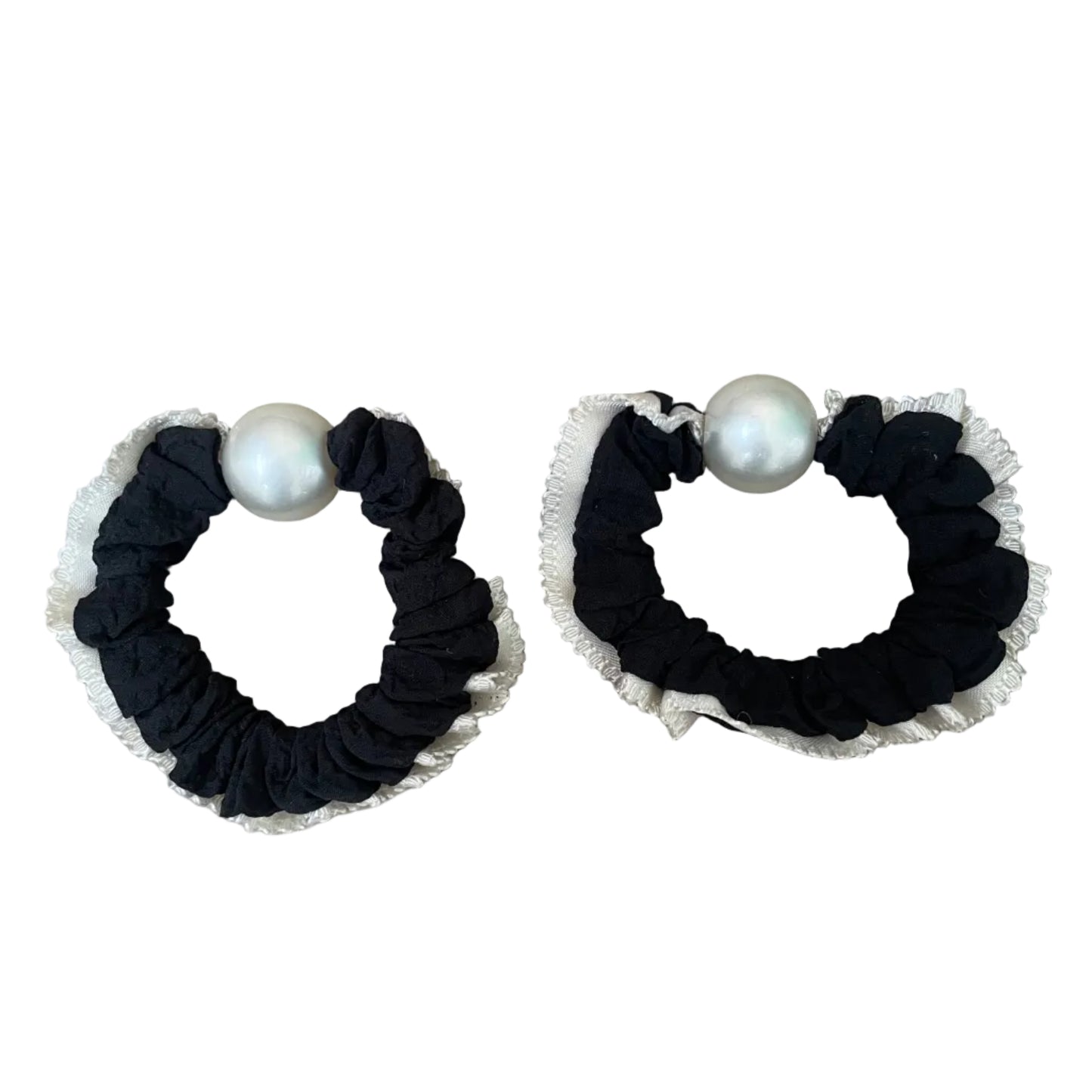 Two black scrunchies with white pearls on a beige background