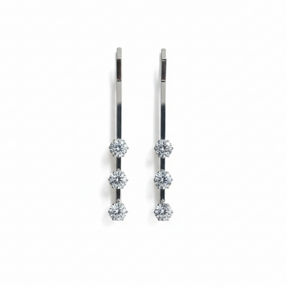Pair of silver pins with multiple gemstones on a white background