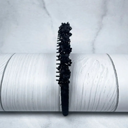 Black embellished headbands for women decorated with beads and floral accents on white textured background