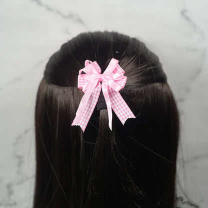 Pink checkered bow clips for kids securing half-up hairstyle on dark brown hair