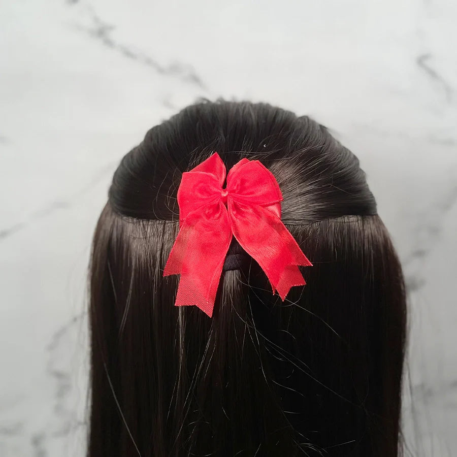 Red bow clips for kids securing half-up hairstyle on dark straight hair with marble background