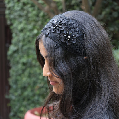 Black broad flower hairbands with floral embellishments worn on dark wavy hair outdoors