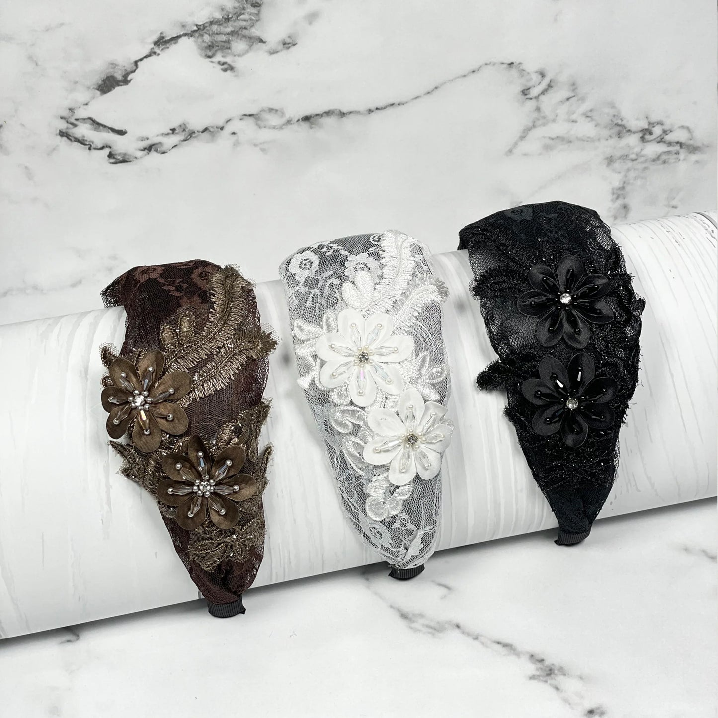 Set of three broad flower hairbands in brown, white, and black lace with floral embellishments