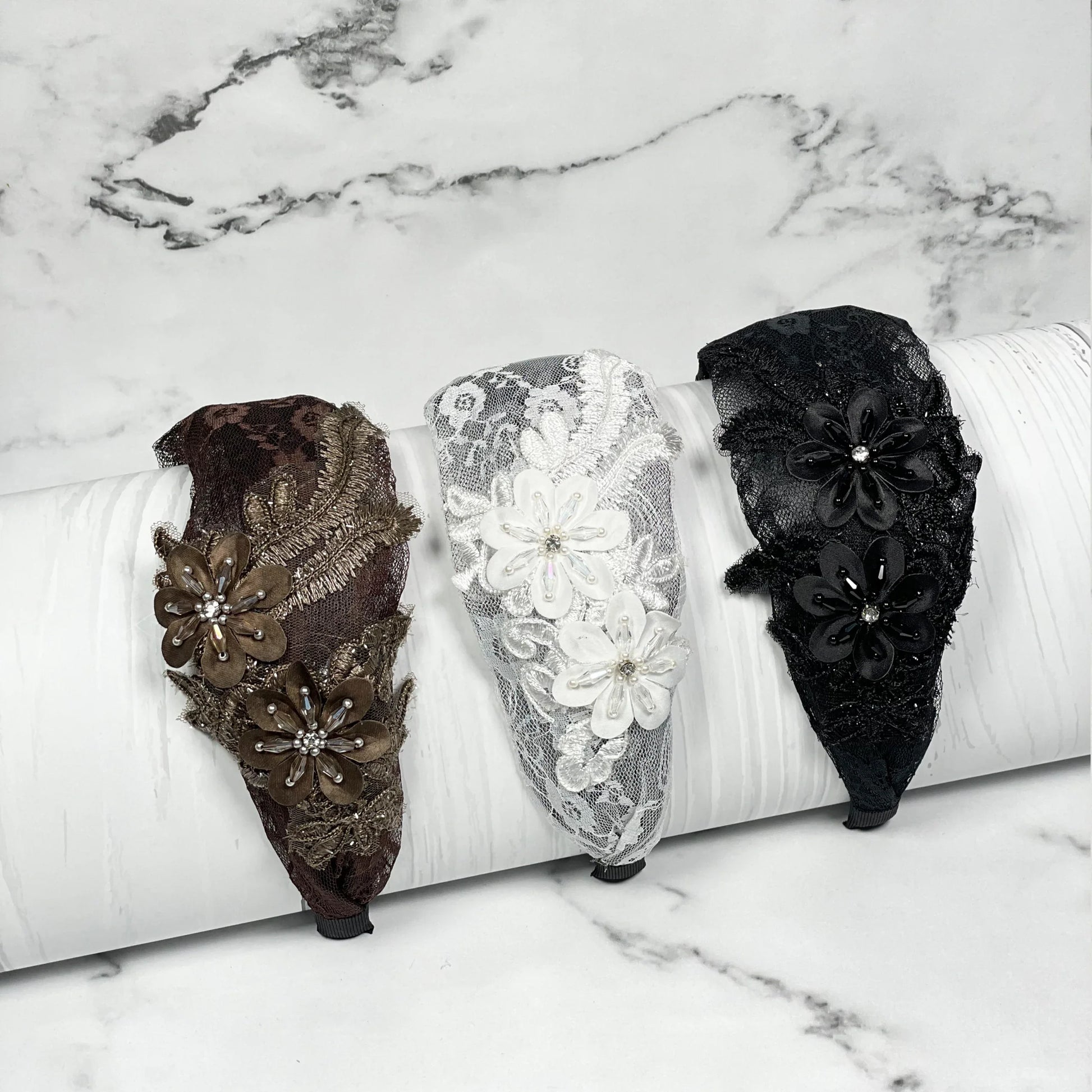 Set of three broad flower hairbands in brown, white, and black lace with floral embellishments