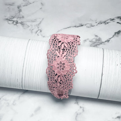 Pink broad lace hairbands with floral pattern displayed on white marble background