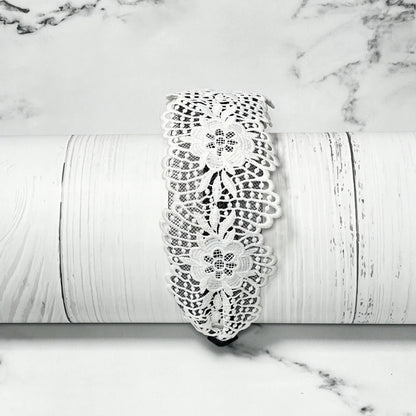 White floral broad lace hairbands with intricate pattern displayed on white textured surface