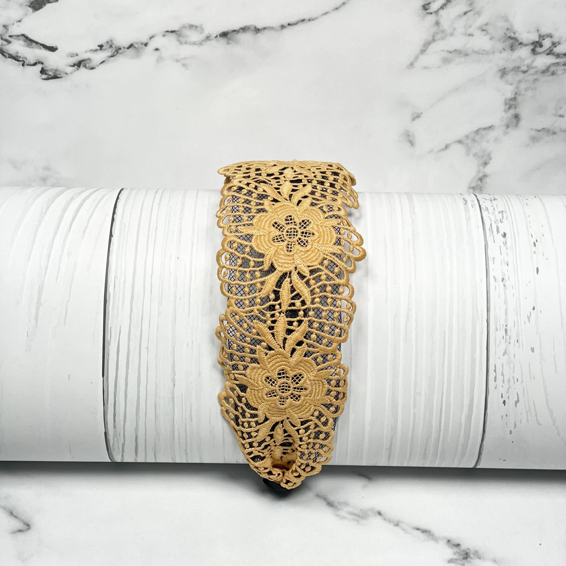 Yellow broad lace hairbands with floral design displayed on white wood background