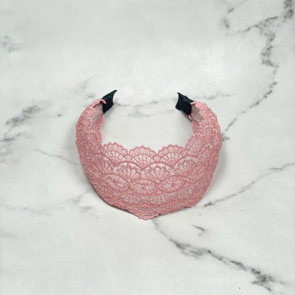 Pink broad lacy hairband with intricate floral lace pattern on a marble surface