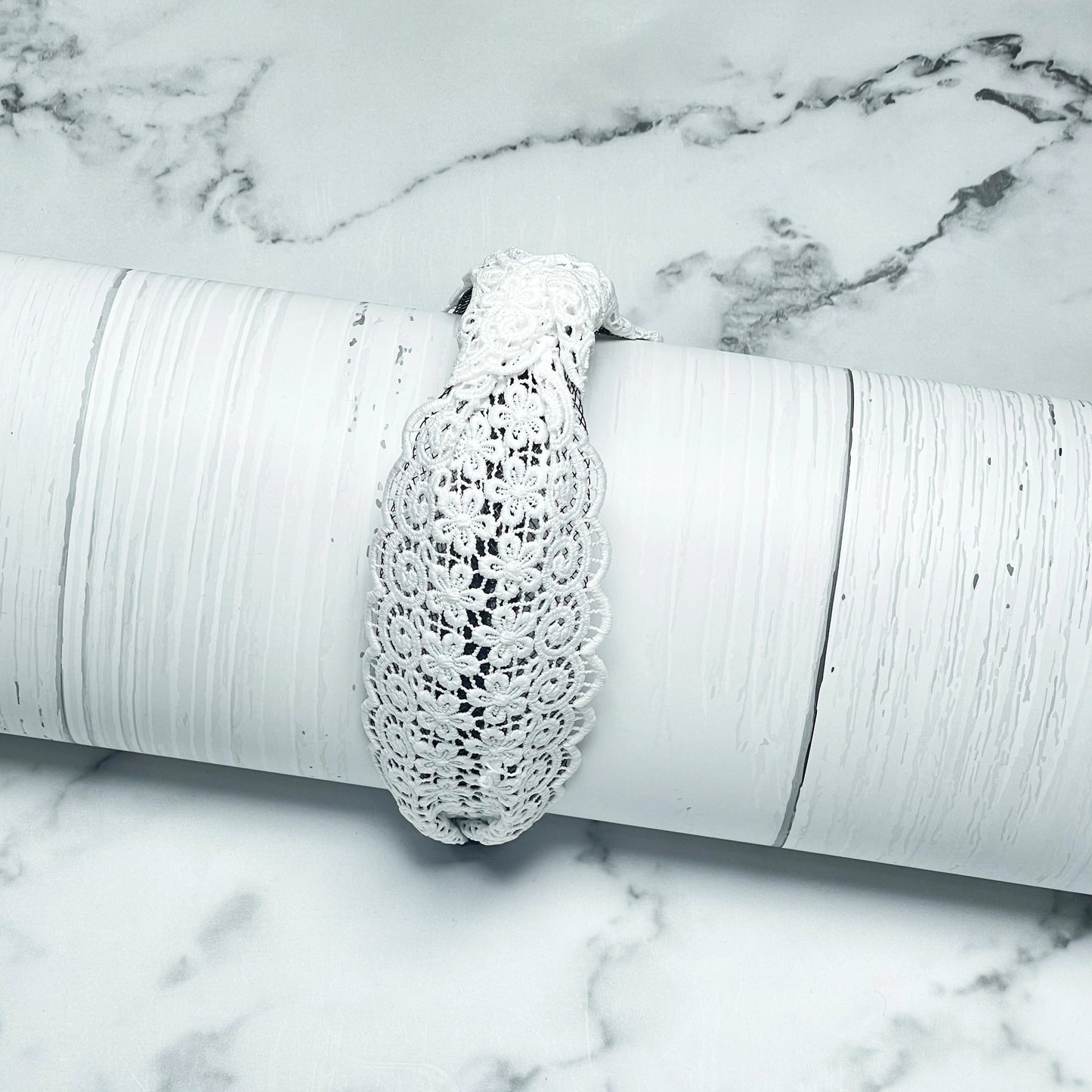 White Broad Lacy Knotted Hairbands displayed on textured white cylindrical prop