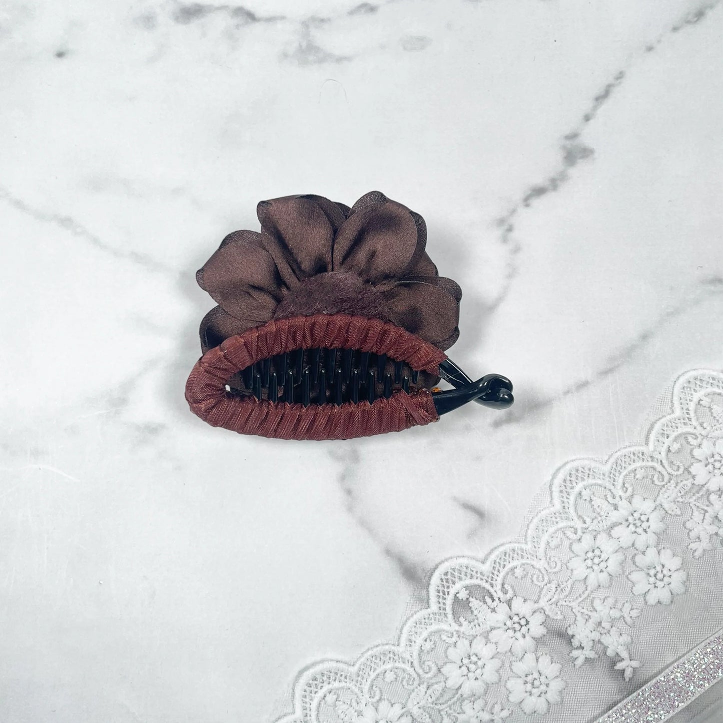 Bella Luxe brown flower crystal banana clip with fabric flower detail on marble surface