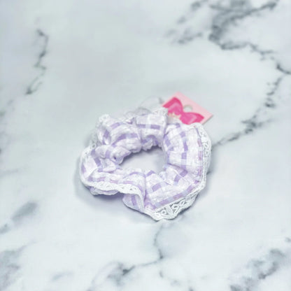 Purple and white check scrunchies with lace detail on marble background