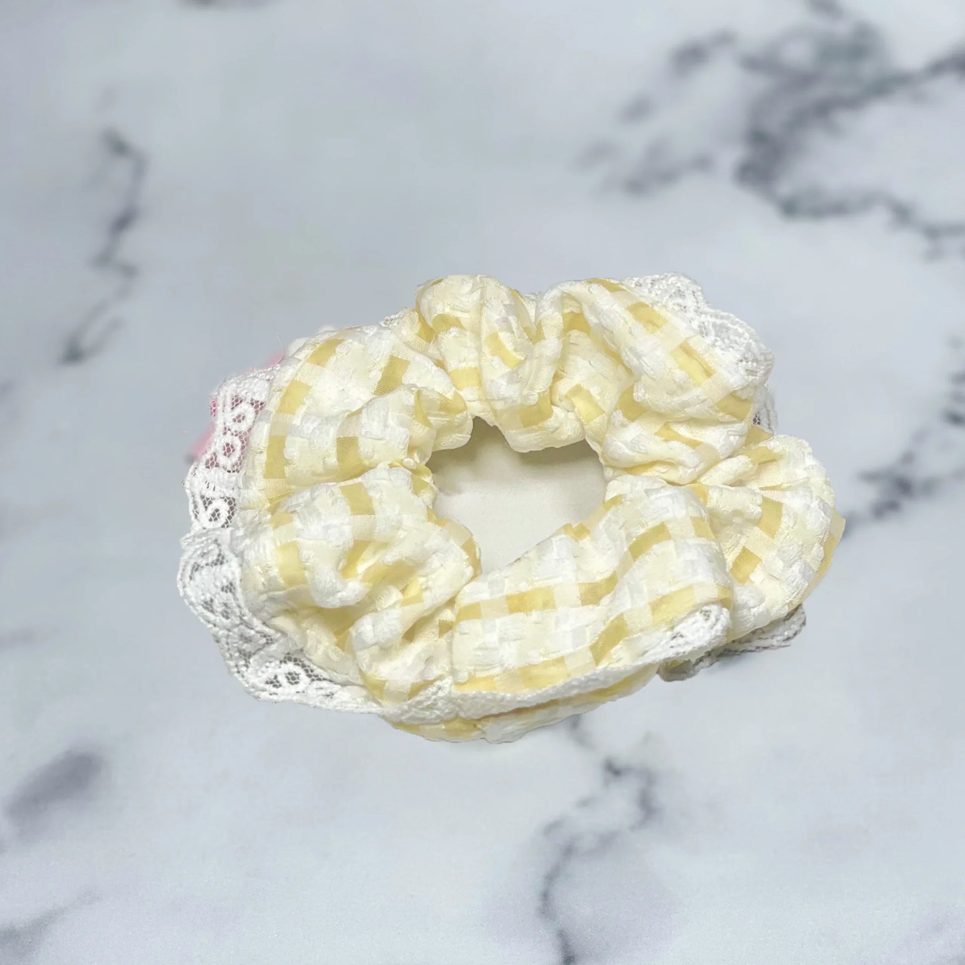 Yellow and white check scrunchies with lace edge on marble surface by mydevelopmentstor