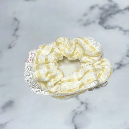 Yellow and white check scrunchies with lace edge on marble surface by mydevelopmentstor