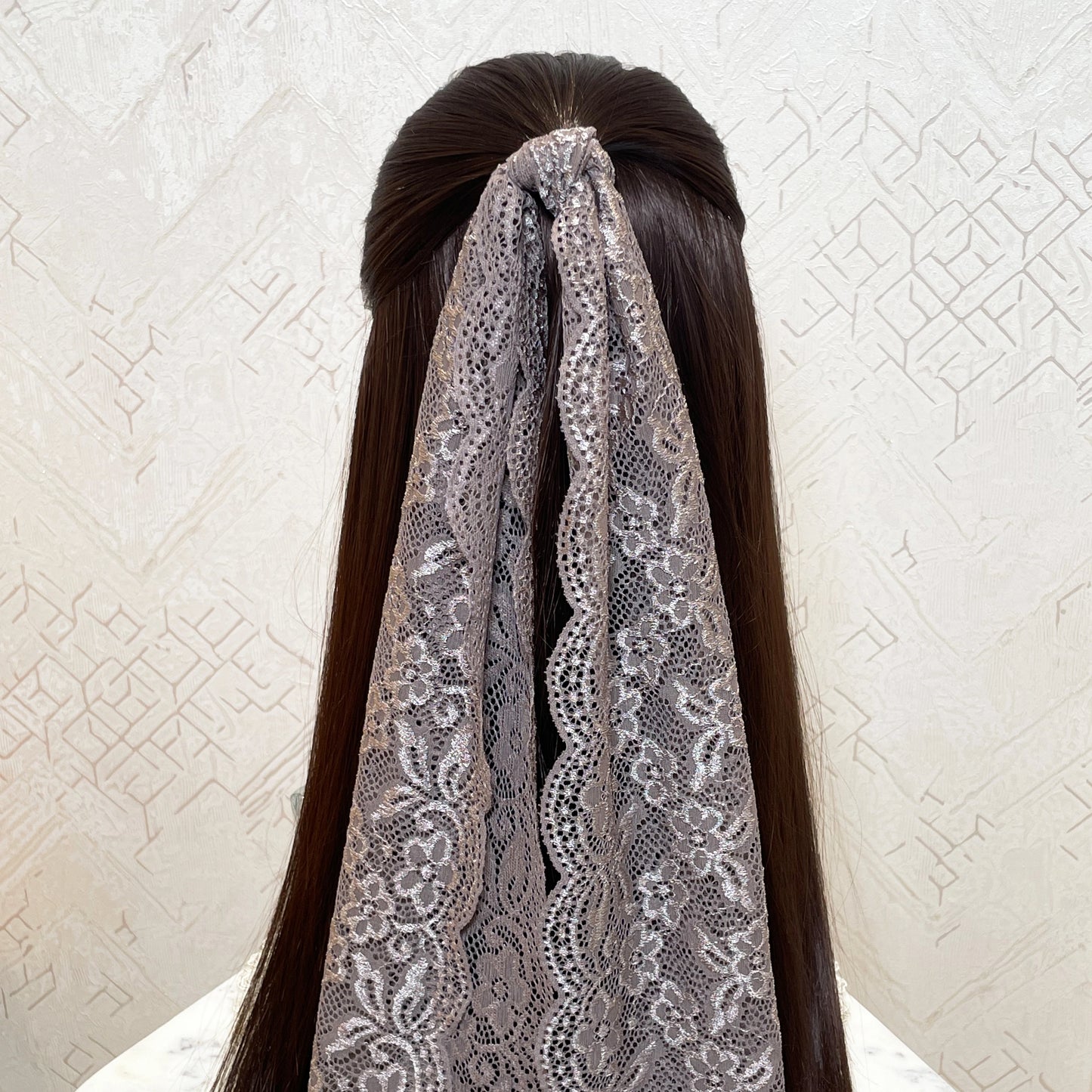 Coffee lacy hair scarf tied at the back of long dark brown hair with floral lace design