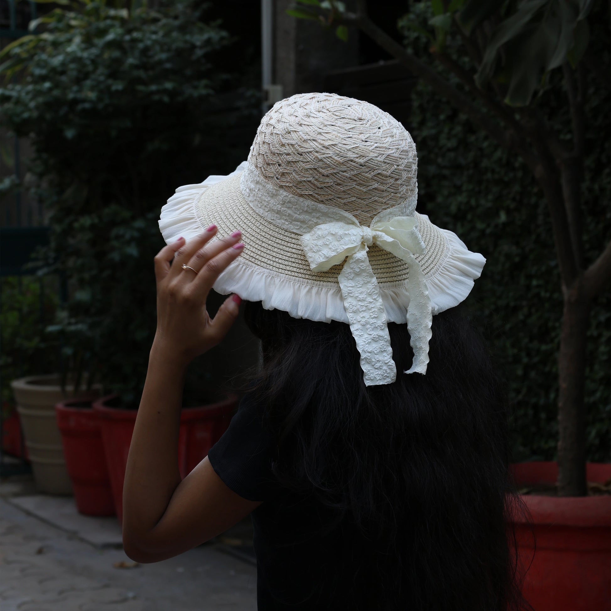 Bella Luxe cream straw braided round hat with bow and ruffled edge worn outdoors